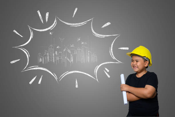 istock A boy wearing a yellow engineer hat and a house plan on a blackboard 1197220573