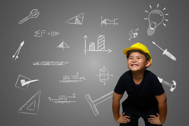 istock A boy wearing a yellow engineer hat and a house plan on a blackboard 1197220594