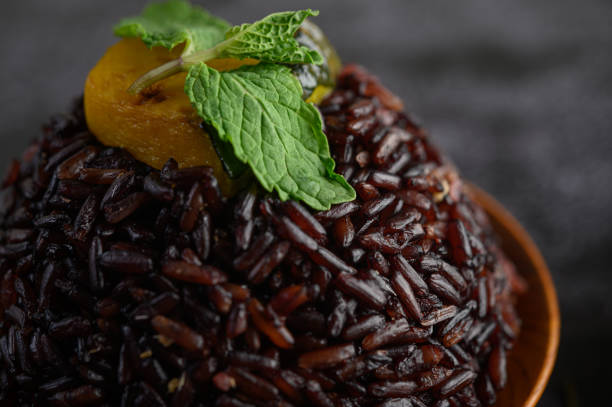 Purple rice berries cooked in a wooden dish with mint leaves and pumpkin. Selective focus