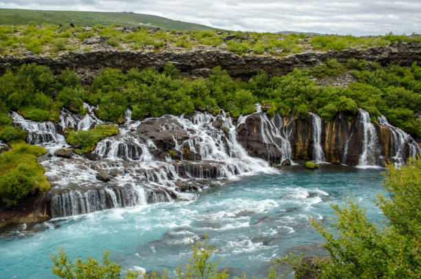 Hraunfossar waterfall in Iceland A series of waterfalls formed by water streaming out of the Hallmundarhraun, a lava field which flowed from an eruption of one of the volcanoes lying under the glacier Langjökull. hraunfossar stock pictures, royalty-free photos & images