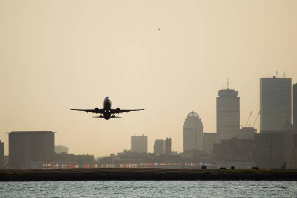 flugzeug startet vom boston logan international airport - boston urban scene skyline sunset stock-fotos und bilder