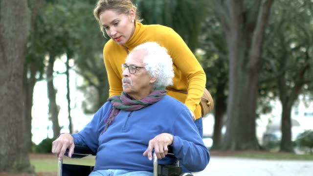 Senior Hispanic man in wheelchair, with adult daughter