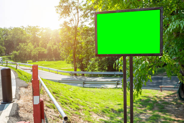 istock Green blank billboard ready for new advertisement at road pathway jogging track in the park 1197233084
