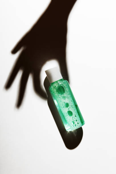 화장품 액체 병 조성물을 들고 손 그림자. 메이크업 제거 클렌징 제품 패키지, 매니큐어 녹색 리무버 모형. 스킨 케어, 바디 케어 로션. 브랜드가 없는 병이 있는 배경 - jar human hand moisturizer packaging 뉴스 사진 이미지