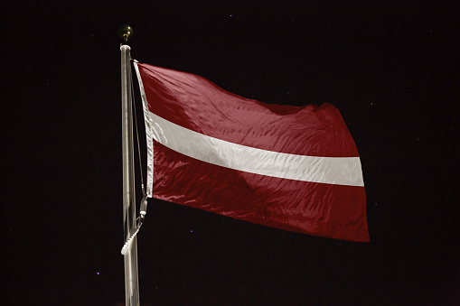 Latvia flag blowing in the wind at night