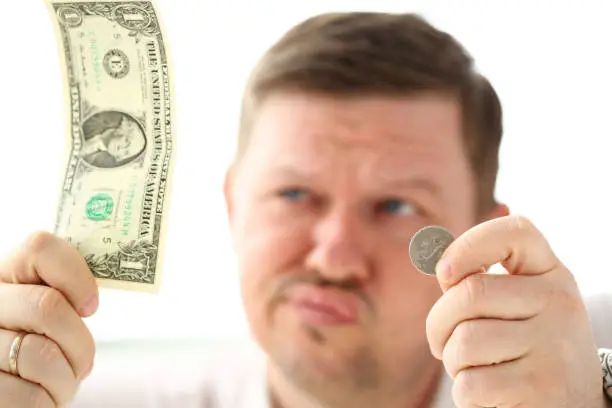 Photo of Arms of thoughtful man holding paper and coin currency