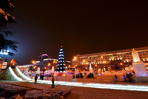 CHELYABINSK, RUSSIA - FEBRUARY 2, 2019:   People walk in illuminated Ice town in the evening  - Revolution square - the Centre of Chelyabinsk. New year's ice town