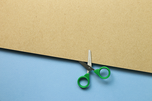 Scissors cutting brown kraft paper