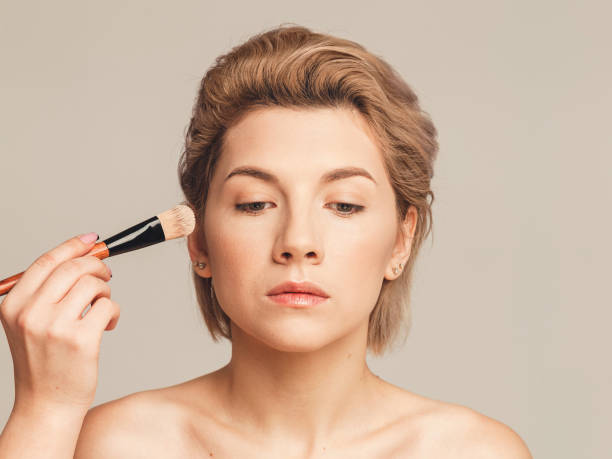 istock applying foundation on a woman's face. Makeup artist training concept. Without retouching 1197252329