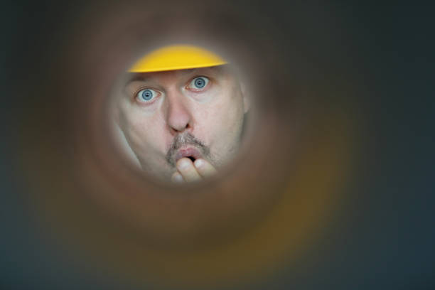 Male plumber looks into contaminated pipe Male plumber looks into contaminated pipe and is very surprised at huge blockage. Sewer pipe repair concept meme photos stock pictures, royalty-free photos & images
