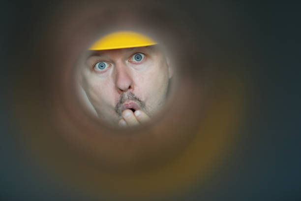 Male plumber looks into contaminated pipe Male plumber looks into contaminated pipe and is very surprised at huge blockage. Sewer pipe repair concept i see you meme stock pictures, royalty-free photos & images