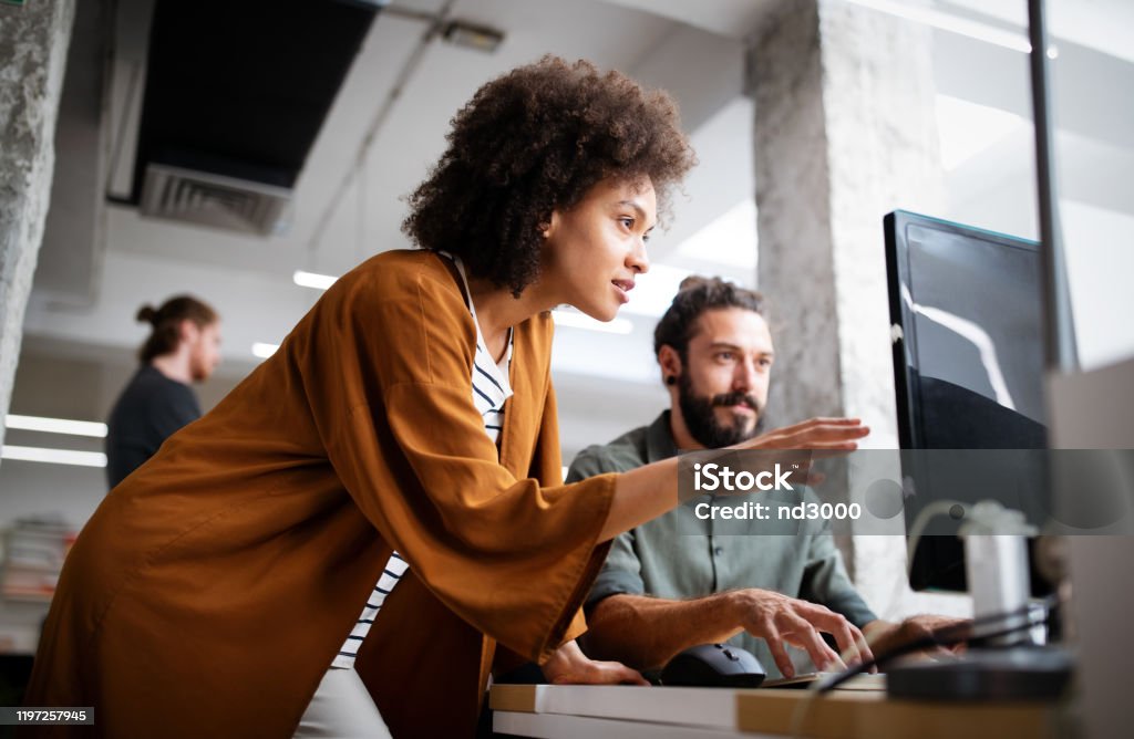 Programmers cooperating at IT company developing apps Programmers working cooperating at IT company developing apps Technology Stock Photo
