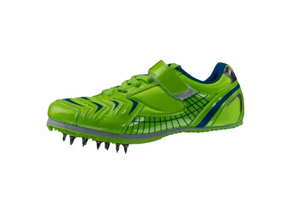 Green glossy sneaker with spikes on a white background. Sport shoes.