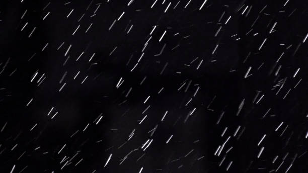 Heavy rain drops on night black background with light. It can be used as luma matte for video production