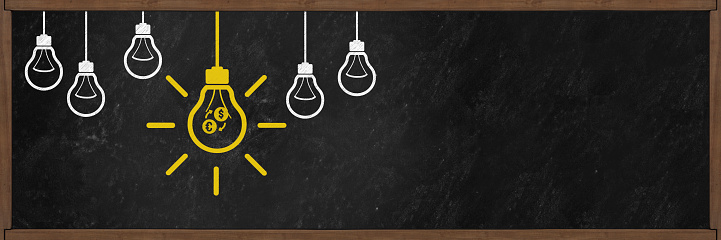 5 Bulb, one of them is yellow which glowing with currency exchange or forex icon on photographic blackboard background. Horizontal panoramic composition with large copy space.