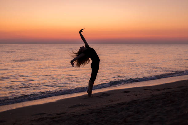 istock Girl dancing on the beach at sunset 1197260813