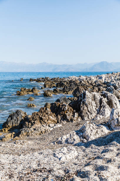 rocky beach on the island of corfu - travel destinations rocky coastline moody sky clear sky imagens e fotografias de stock