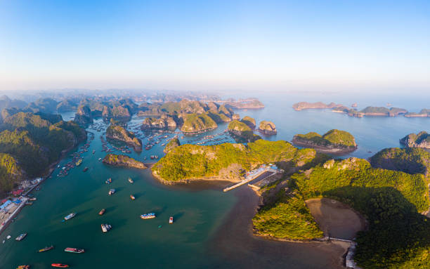 Aerial sunset view of Lan Ha bay and Cat Ba island, Vietnam, unique limestone rock islands and karst formation peaks in the sea, floating fishermen villages and fish farms from above. Clear blue sky. Aerial sunset view of Lan Ha bay and Cat Ba island, Vietnam, unique limestone rock islands and karst formation peaks in the sea, floating fishermen villages and fish farms from above. Clear blue sky. haiphong province photos stock pictures, royalty-free photos & images