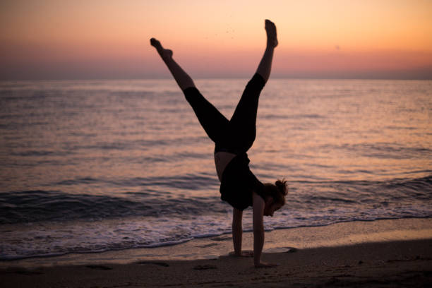 Silhouette of an energetic girl dancing ballet on the beach at sunset