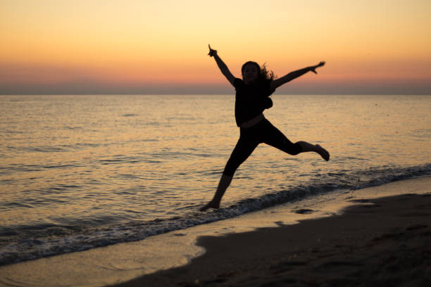 Silhouette of an energetic girl dancing ballet on the beach at sunset