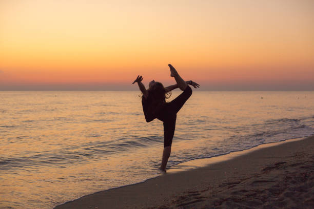 Silhouette of an energetic girl dancing ballet on the beach at sunset
