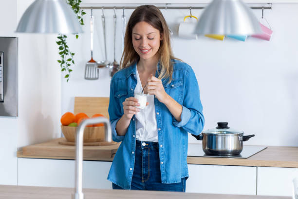 istock Pretty young woman eating yogurt while standing in the kitchen at home. 1197263111
