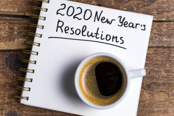 istock New year resolutions 2020 on desk. 2020 goals list with notebook, coffee cup on wooden background. Goals, plan, strategy, change, action, idea 1197266034