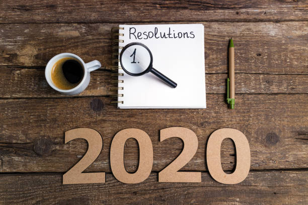 istock New year resolutions 2020 on desk. 2020 goals list with notebook, coffee cup, magnifier on wooden background. Goal, plan, strategy, change, idea concept 1197266083