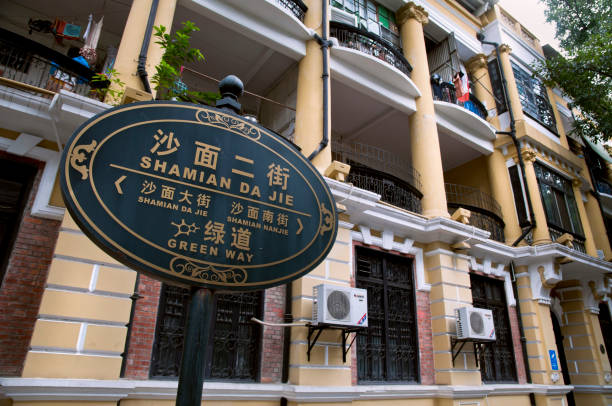Macau / Macao, China - December 29, 2018: Road sign placard written in Portuguese and Chinese as the Portugal heritage in this city.Formerly a Portuguese colony, the territory of Portuguese Macau was first leased to Portugal by the Ming dynasty as a trading post in 1557. Portugal paid an annual rent and administered the territory under Chinese sovereignty until 1887. Portugal later gained perpetual colonial rights in the Sino-Portuguese Treaty of Peking. In those days Macao / Macau is referred to as the \