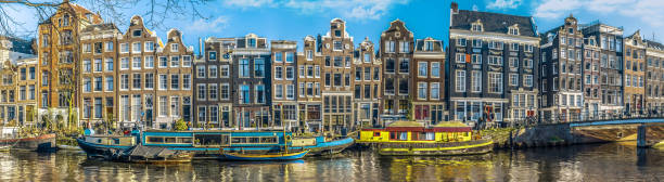 Panorama of canal houses in Amsterdam Grachtengordel binnenstad..
Singel aan de Amstel. In het water liggen de woonboten.
De huizen hebben historische gevels en zijn gebouwd in de 17e eeuw. house with moat stock pictures, royalty-free photos & images