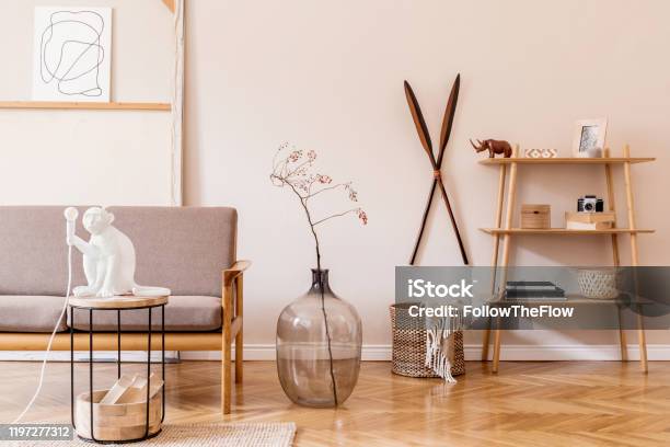 Stylish Interior Design Of Living Room At Cozy Apartment With Brown Sofa Coffee Table With Lamp Bookstand Vase And Elegant Accessories Minimalistic Concept Of Home Staging Beige Wall Template Stock Photo - Download Image Now