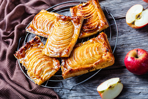 close-up of Caramel Apple  puff pastry tarts on a metal stand on a wooden rustic table with brown cloth