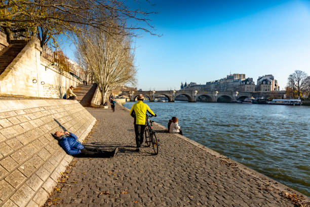 Bearded middle aged man standing by the fence on a bridge over the Seine River on a sunny day and looking at camera, short city break, perfect weekend