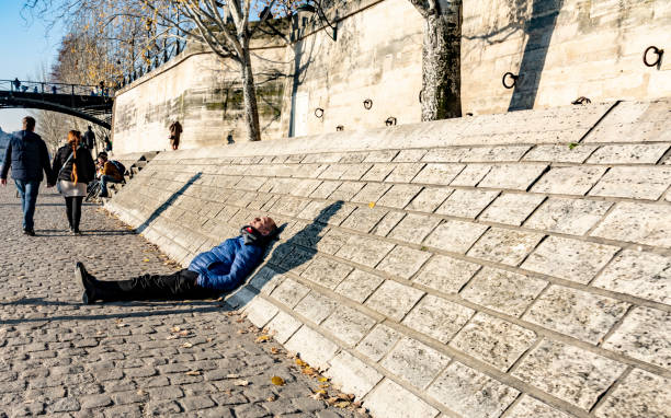 2019 People in Paris on the embankment. They are walking beside the River Seine with late afternoon winter sun. Paris, France.