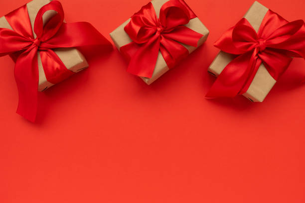 istock Three gift boxes wrapped on red ribbons on red background. Valentines day or Mothers day celebration concept. Top view. copy space 1197284325