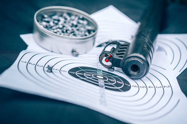 воздушная винтовка, патроны и бумажная мишень на черном фоне, вид сверху, спортивная стрельба - rifle sport air target shooting стоковые фото и изображения