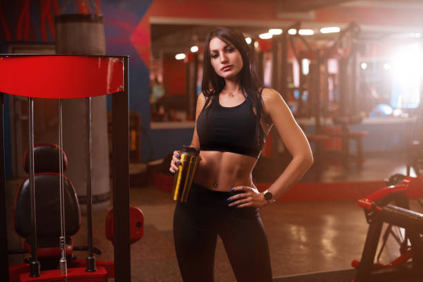 sporty young woman with protein cocktail in a shaker in a gym. sports nutrition concept - body building milk shake protein drink drink imagens e fotografias de stock