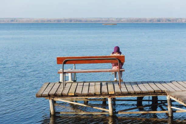 istock The child sits on a bench by the river. 1197288790