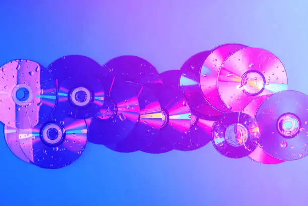 Photo of CDs on a plain background illuminated with neon light pink blue, minimal style