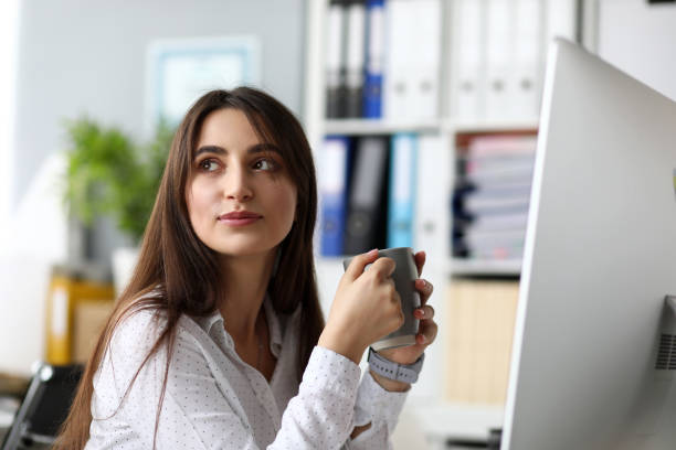 istock Positive cheerful female sitting at worktable drinking water 1197289498