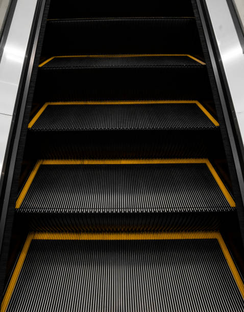 istock Modern escalator electronic system moving. Escalator is moving up.The ground is a straight line. Black with yellow band. 1197291080