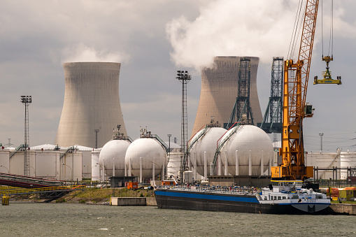 Antwerp, Belgium - June 8th, 2019: View over some petrochemical industry installations in the port of Antwerp to the Nuclear Power Plant Doel with its two cooling towers.