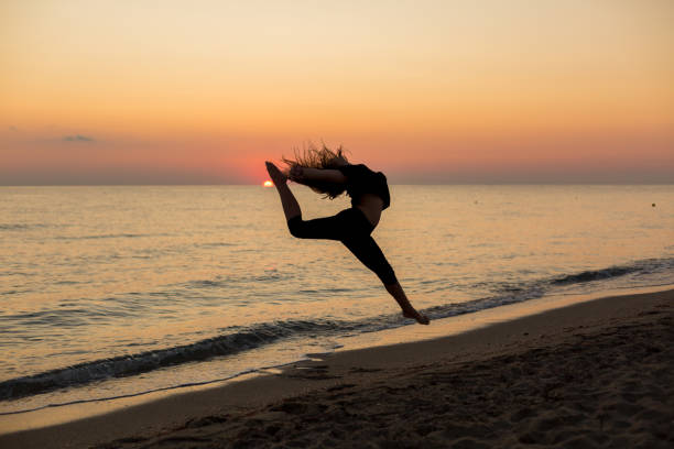 istock Girl dancing on the beach at sunset 1197292081