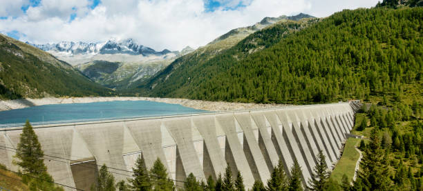 Grand barrage en béton avec des paysages de lac, de forêt et de hautes montagnes. Voyage Italie. - Photo