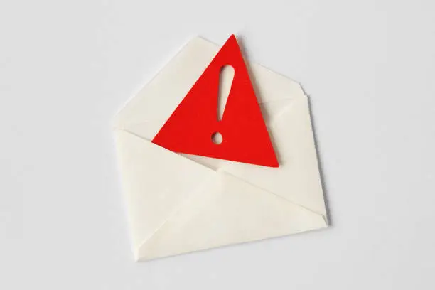 Photo of Email envelope with warning sign on white background