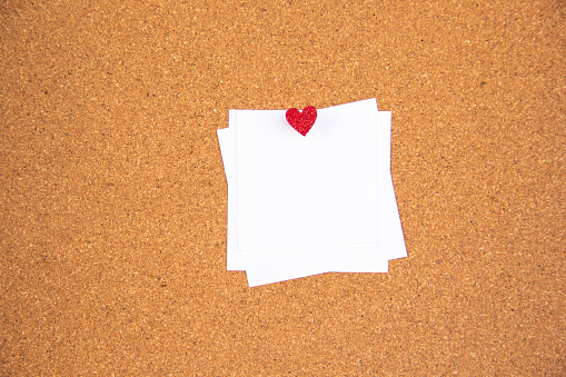 3 white stickers pinned to a pin with small heart heart on cork board