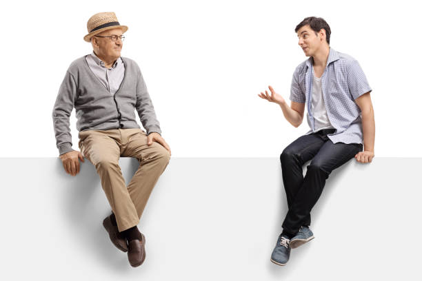 istock Elderly man and a young guy talking and sitting on a blank panel 1197296815