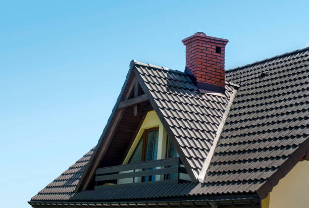 Toit avec tuiles brunes, cheminée rouge faite par la brique et grenier avec balcon contre le ciel bleu. Fond de maison. - Photo