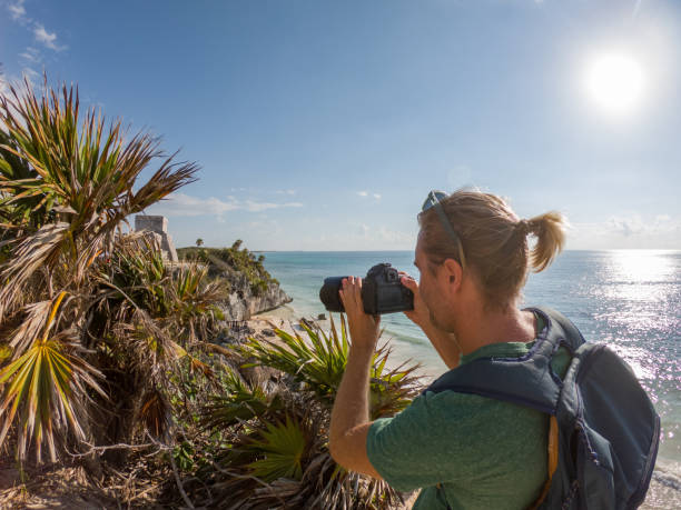 istock Young man taking picture of Tulum ruins using camera, Mexico 1197298895