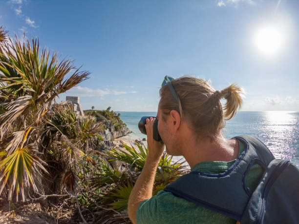 istock Young man taking picture of Tulum ruins using camera, Mexico 1197299119